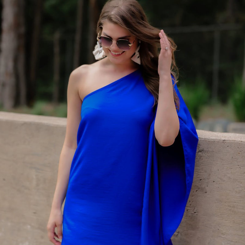 a royal blue one-shoulder mini dress with an asymmetrical neckline and a draping, billowy body creating a relaxed silhouette