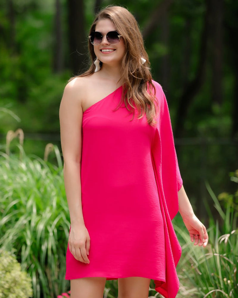 a magenta one-shoulder mini dress with an asymmetrical neckline and a draping, billowy body creating a relaxed silhouette