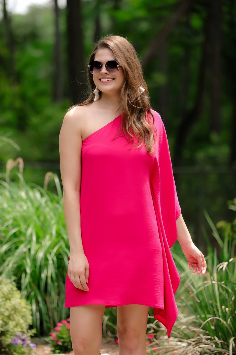 a magenta one-shoulder mini dress with an asymmetrical neckline and a draping, billowy body creating a relaxed silhouette