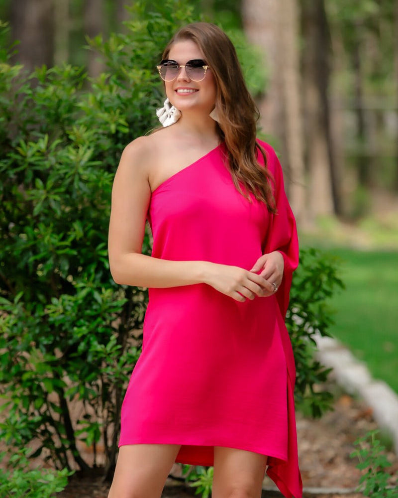 a magenta one-shoulder mini dress with an asymmetrical neckline and a draping, billowy body creating a relaxed silhouette