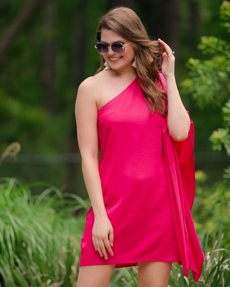 a magenta one-shoulder mini dress with an asymmetrical neckline and a draping, billowy body creating a relaxed silhouette
