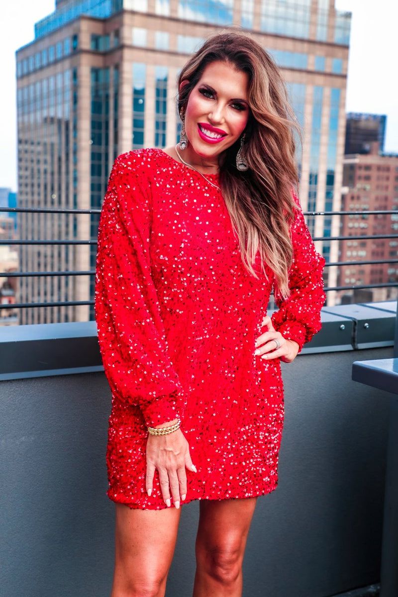 a red long balloon sleeve dress made of sparkly allover sequins, luxe velvet underlay, a keyhole accented upper back with button closure, a round neckline, and subtle elastic cuffs