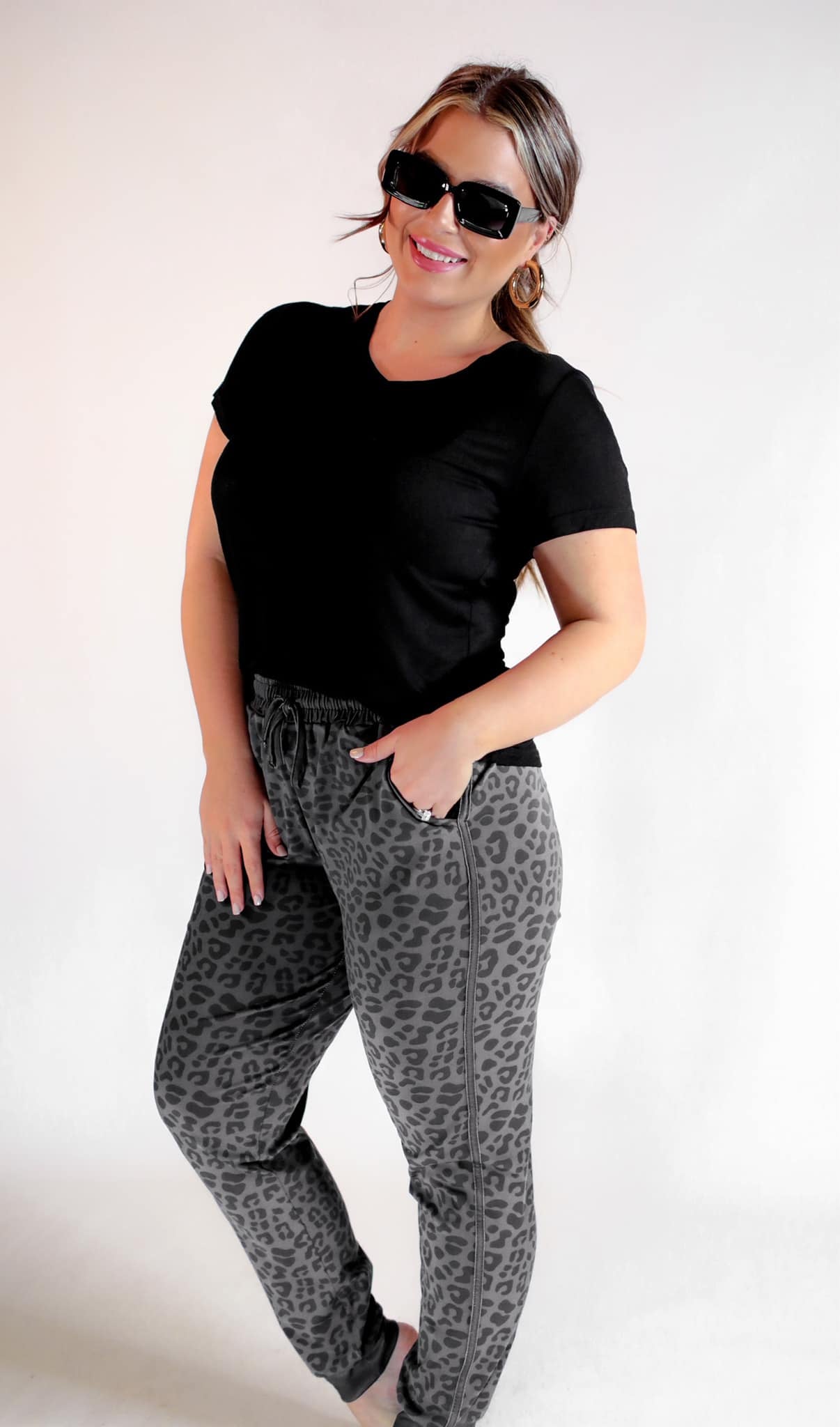 a mid-rise relaxed fit joggers with side pockets and a tie waist drawstring, designed on a black-on-black leopard pattern print and black base