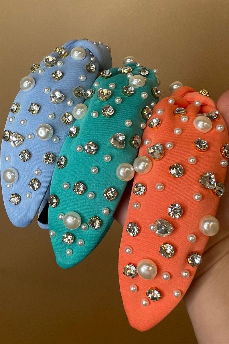 a twisted center knot headband with varying sizes of pearl and rhinestone detailing in blue, coral, and teal