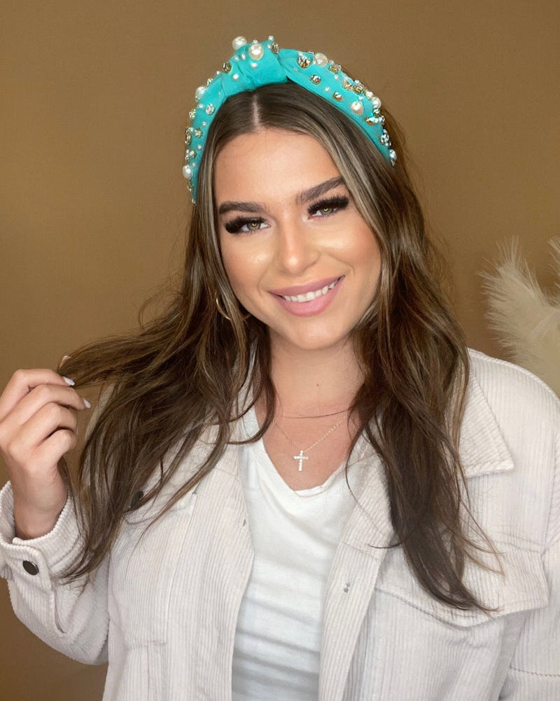 a twisted center knot headband with varying sizes of pearl and rhinestone detailing in teal