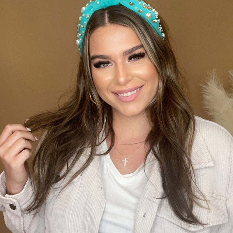 a twisted center knot headband with varying sizes of pearl and rhinestone detailing in teal