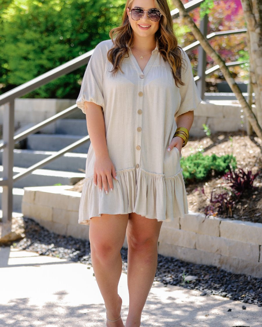 relaxed short-sleeve dress with a V-cut collar, full-button front closure, side pockets, and tiered ruffled hemline in oatmeal