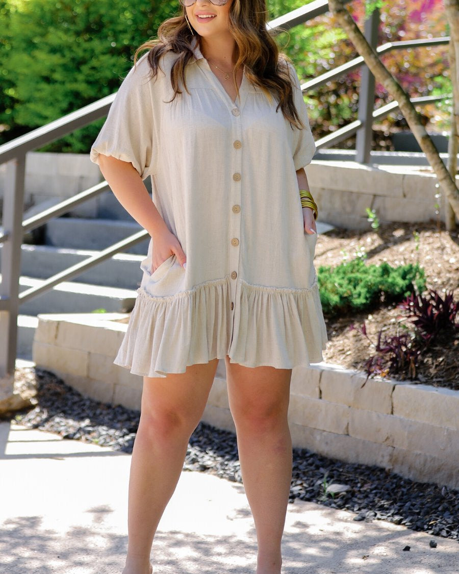 relaxed short-sleeve dress with a V-cut collar, full-button front closure, side pockets, and tiered ruffled hemline in oatmeal