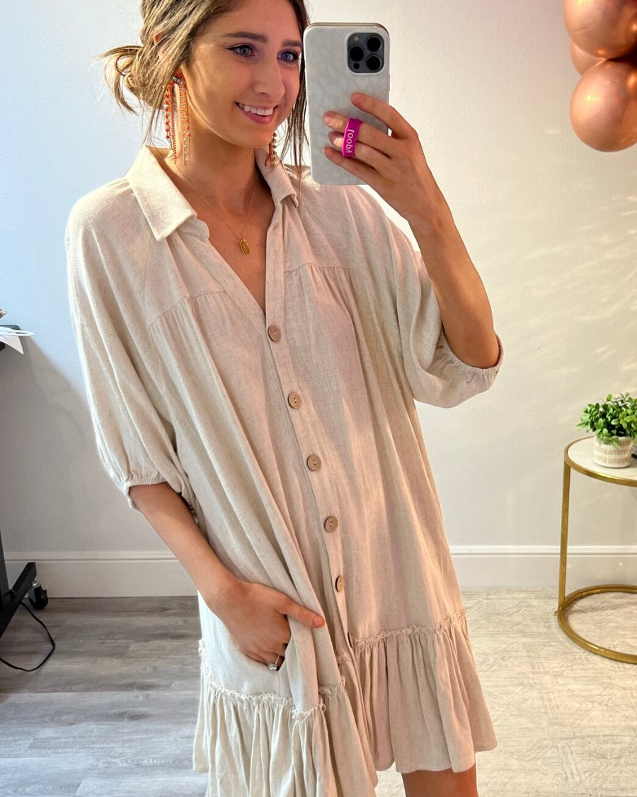 relaxed short-sleeve dress with a V-cut collar, full-button front closure, side pockets, and tiered ruffled hemline in oatmeal