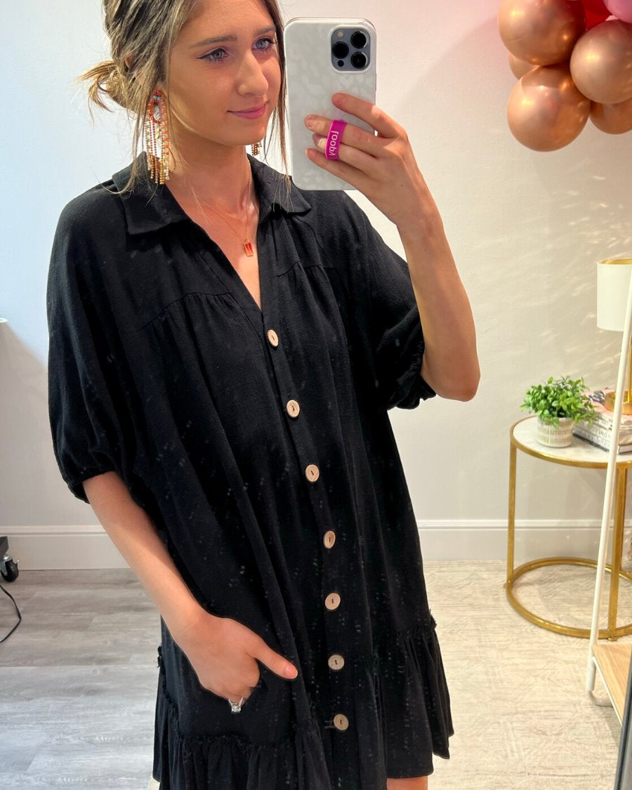 relaxed short-sleeve dress with a V-cut collar, full-button front closure, side pockets, and tiered ruffled hemline in black