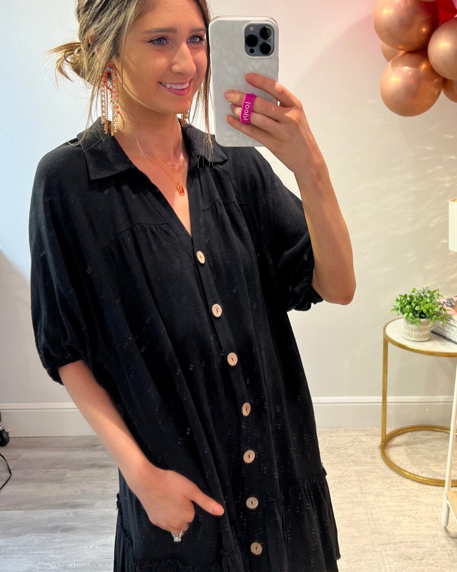 relaxed short-sleeve dress with a V-cut collar, full-button front closure, side pockets, and tiered ruffled hemline in black