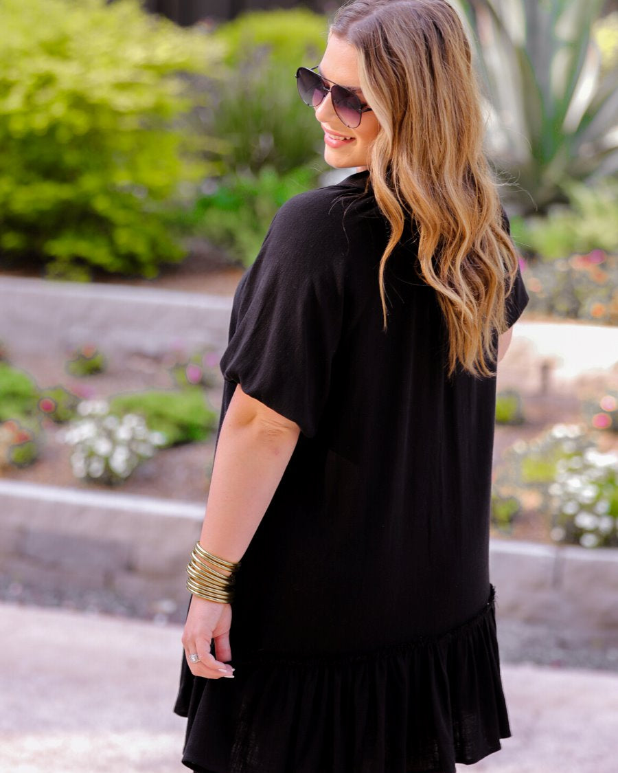 relaxed short-sleeve dress with a V-cut collar, full-button front closure, side pockets, and tiered ruffled hemline in black