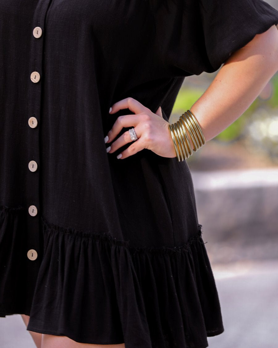 relaxed short-sleeve dress with a V-cut collar, full-button front closure, side pockets, and tiered ruffled hemline in black