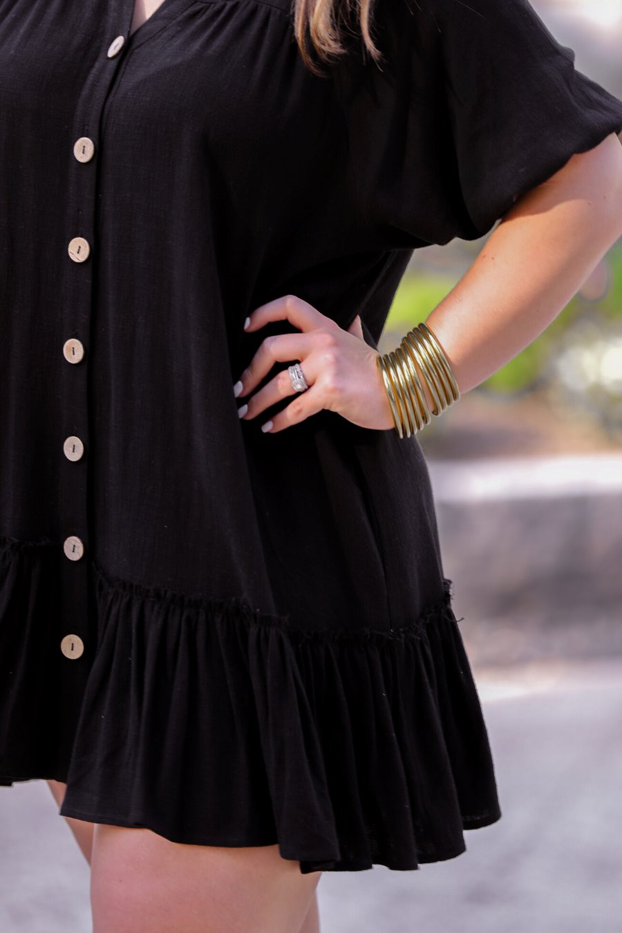 relaxed short-sleeve dress with a V-cut collar, full-button front closure, side pockets, and tiered ruffled hemline in black
