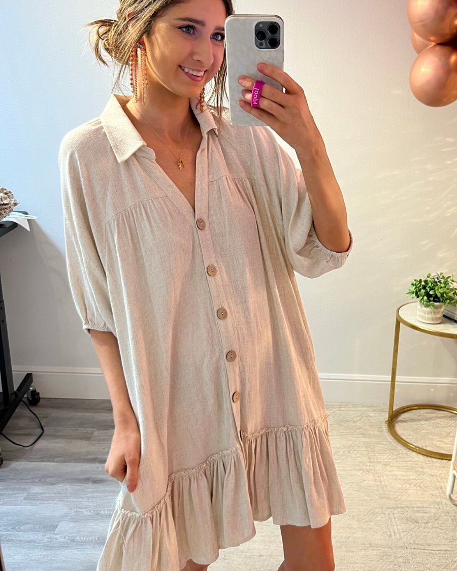 relaxed short-sleeve dress with a V-cut collar, full-button front closure, side pockets, and tiered ruffled hemline in oatmeal