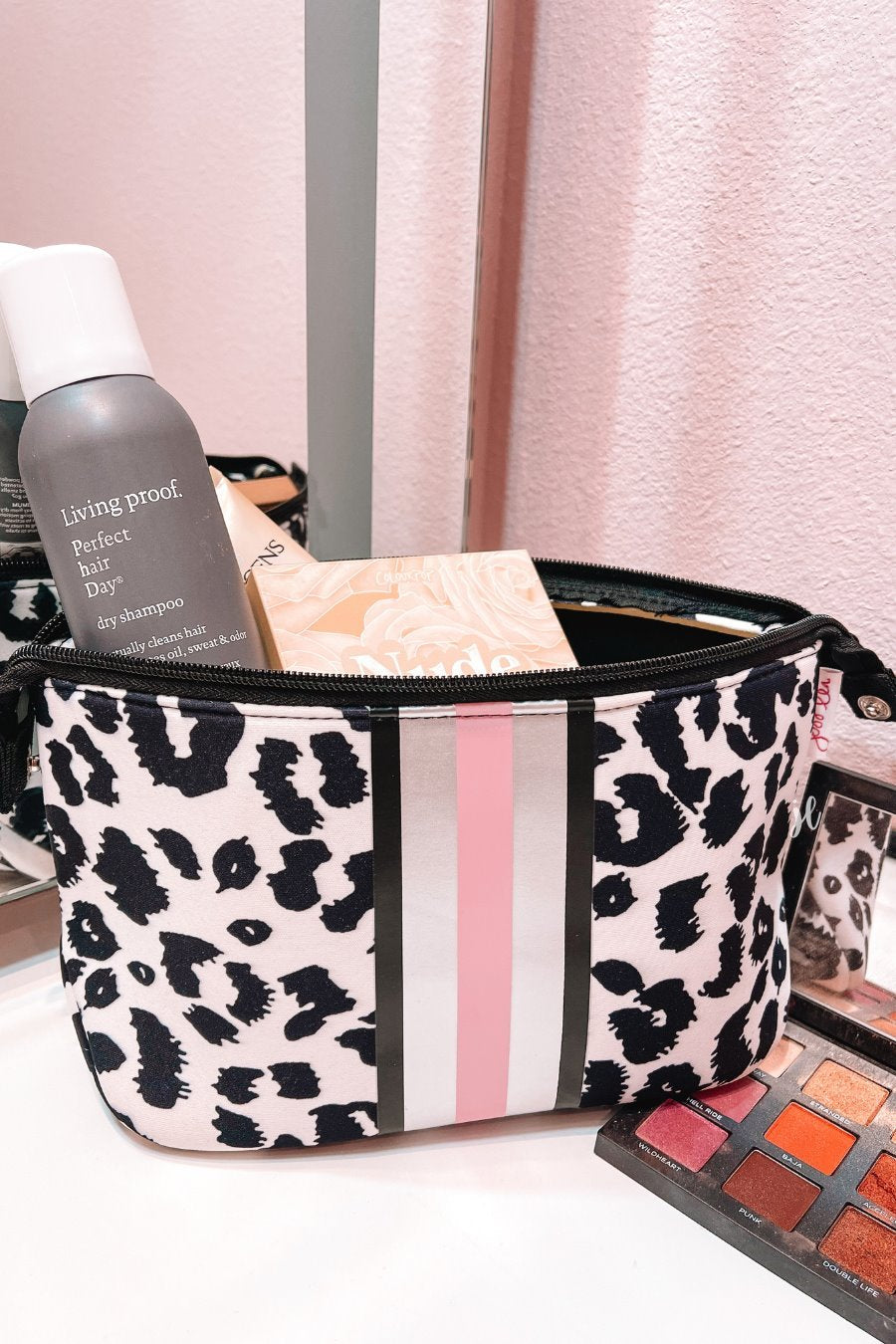 neoprene cosmetic bag in a black and pink leopard print with dual top zippers (black), expandable side snaps (silver), and racing stripes (black, gray, and pink)