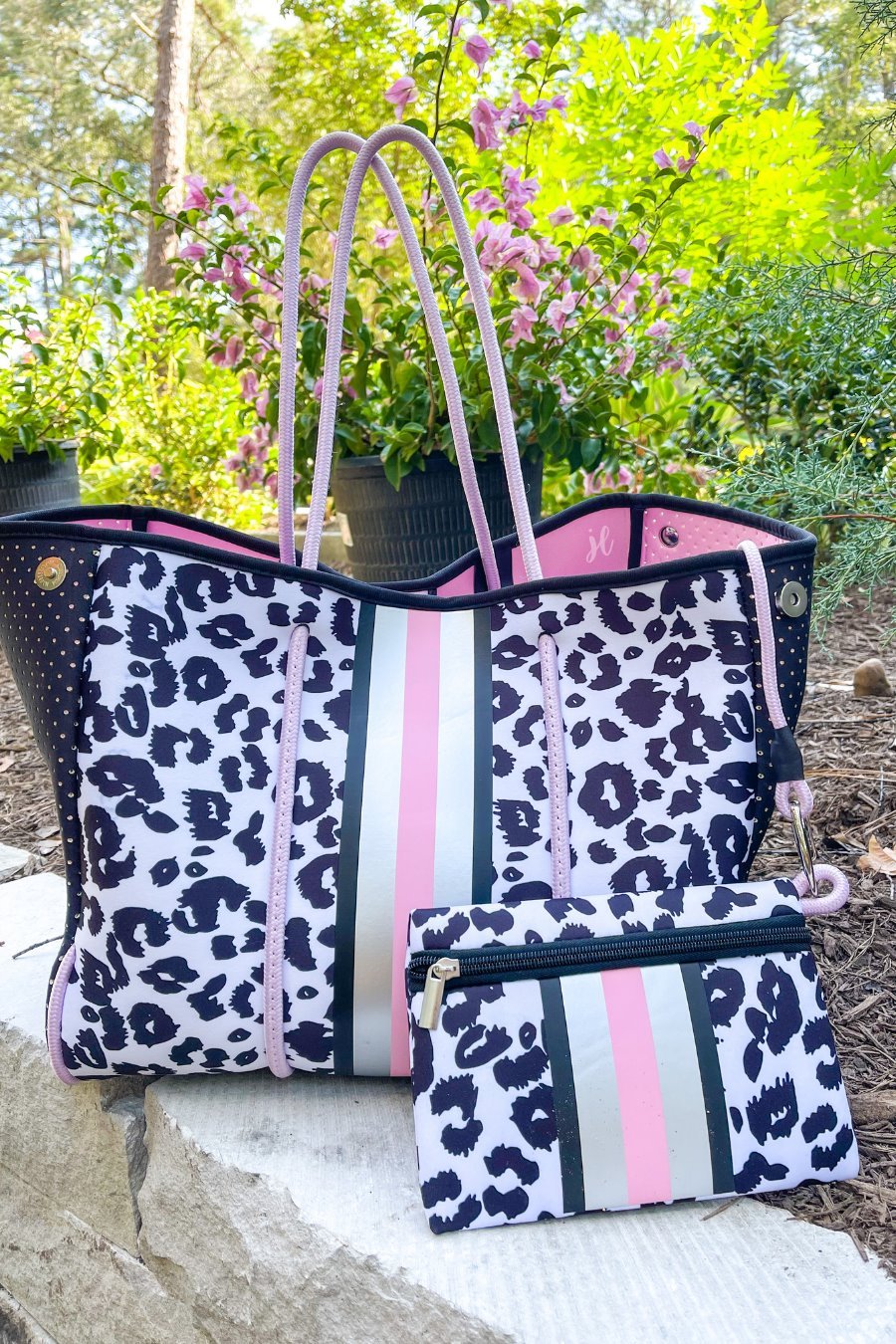 ultra-lightweight tote made of neoprene with a removable hard bottom liner, paracord shoulder straps, removable matching zippered pouch, magnetic side snap closures in silver hardware, black interior (tote and pouch), and racing stripes (black, pink, and white) on a black and pink leopard print pattern