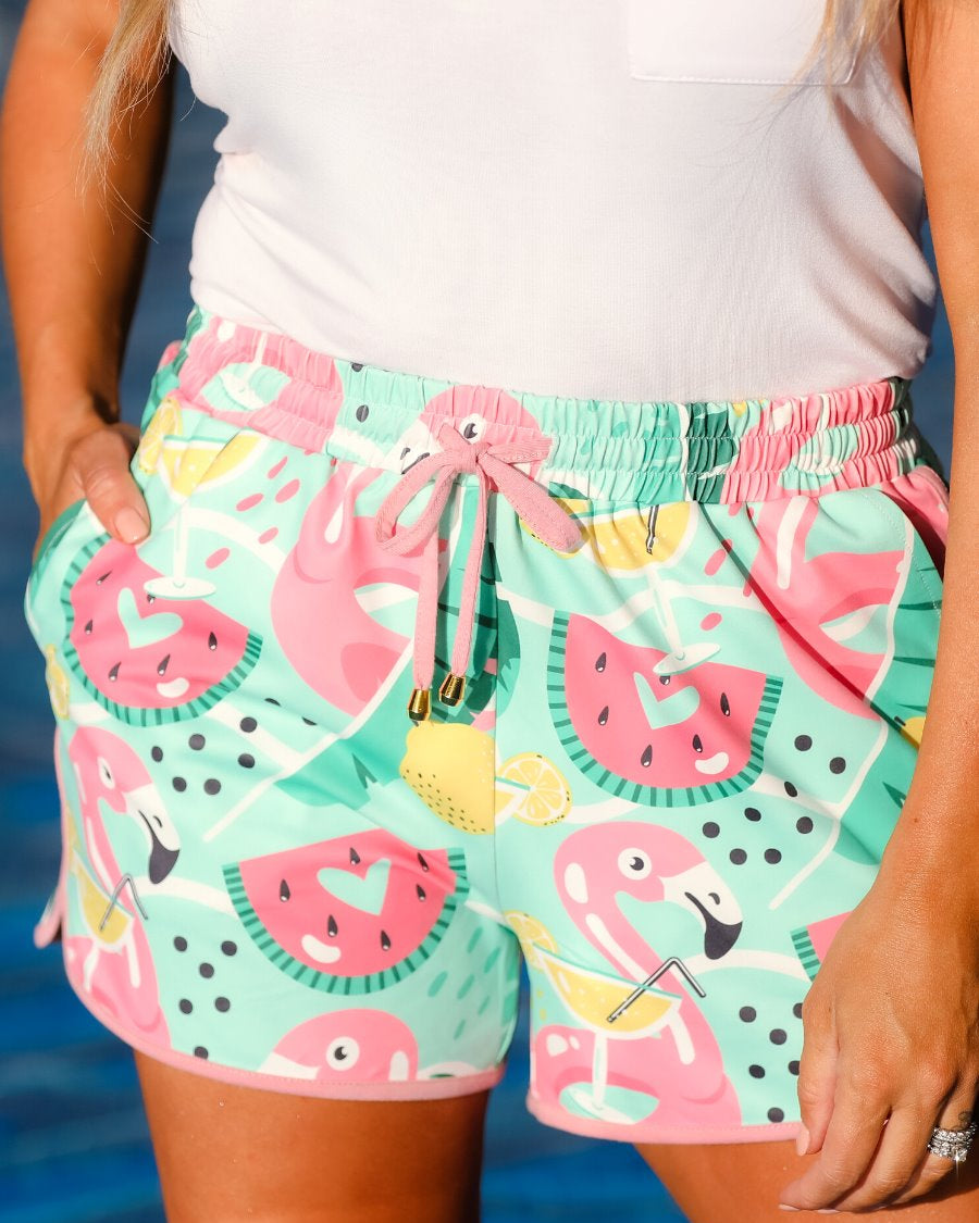 mid-rise relaxed fit activewear shorts with side pockets and a tie waist drawstring with gold bead accents, designed on a playful pool floaties patterned print fabric, mint base, and mauve trim