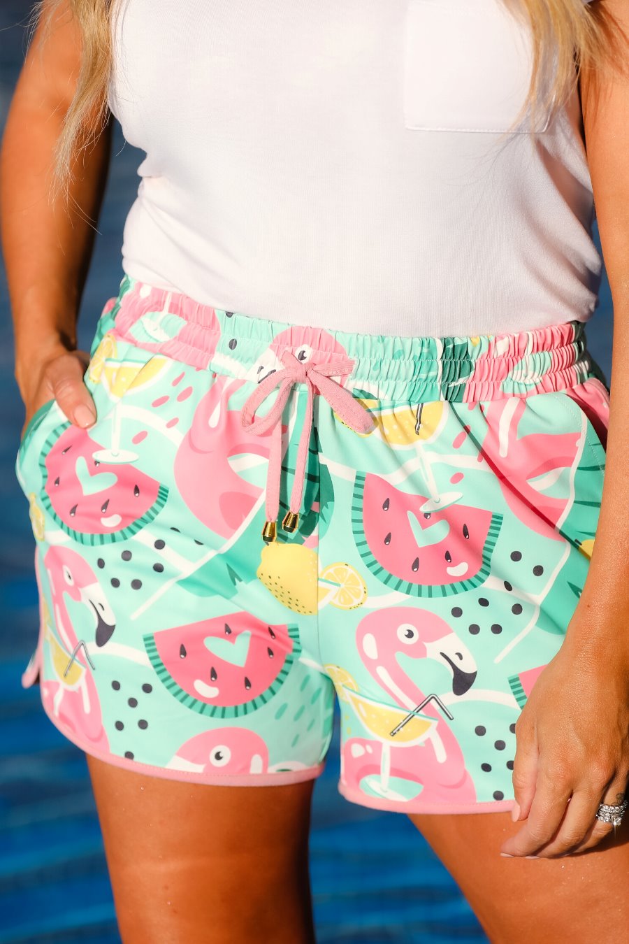 mid-rise relaxed fit activewear shorts with side pockets and a tie waist drawstring with gold bead accents, designed on a playful pool floaties patterned print fabric, mint base, and mauve trim