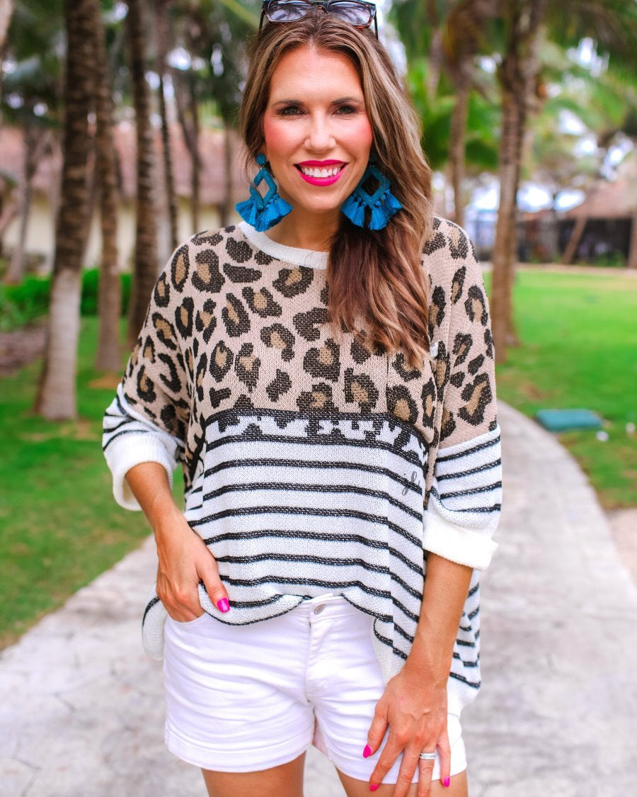 three-quarter cuffed sleeve unlined sweater crafted from loose knit material with an oversized fit, a rounded neckline, a chest pocket, and trim on the collar, hem, and pocket on a mix of leopard print (black, brown, and cream) and vertical stripes (black and ivory)