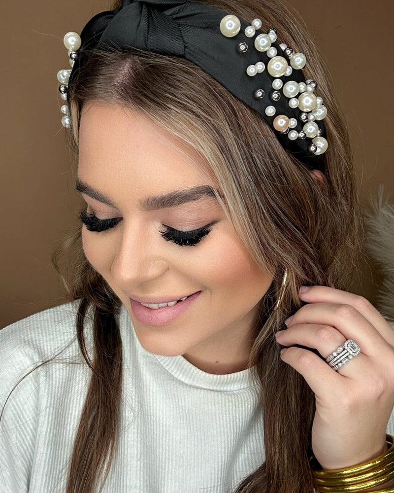 a twisted center knot headband with varying sizes of pearl detailing in black