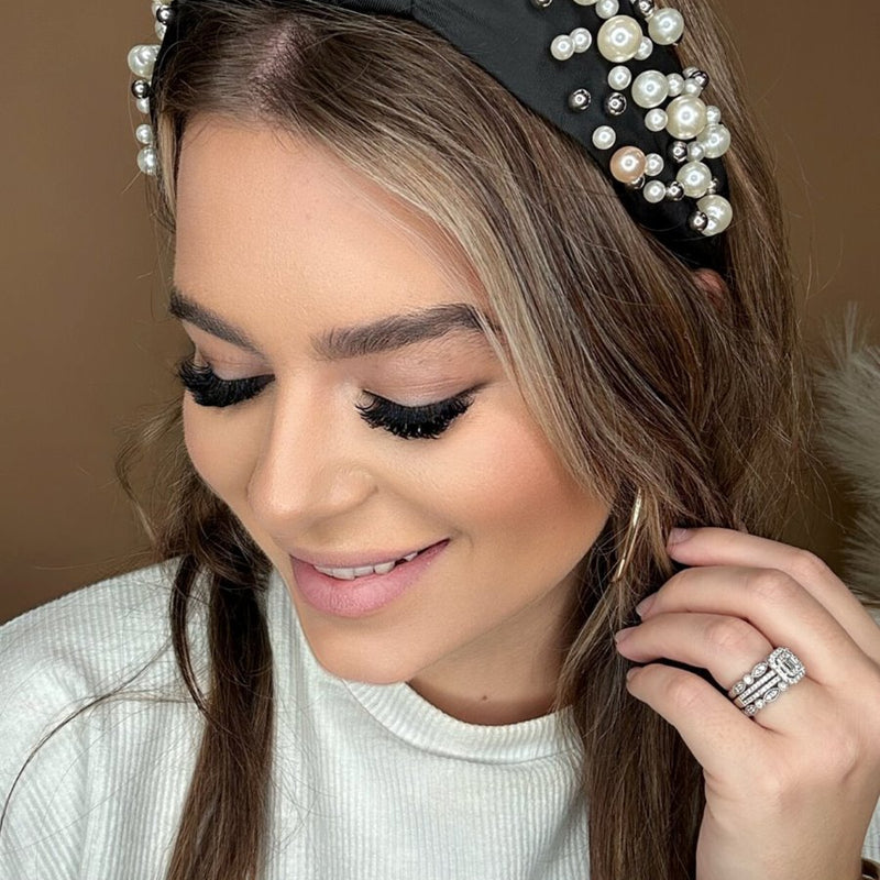 a twisted center knot headband with varying sizes of pearl detailing in black