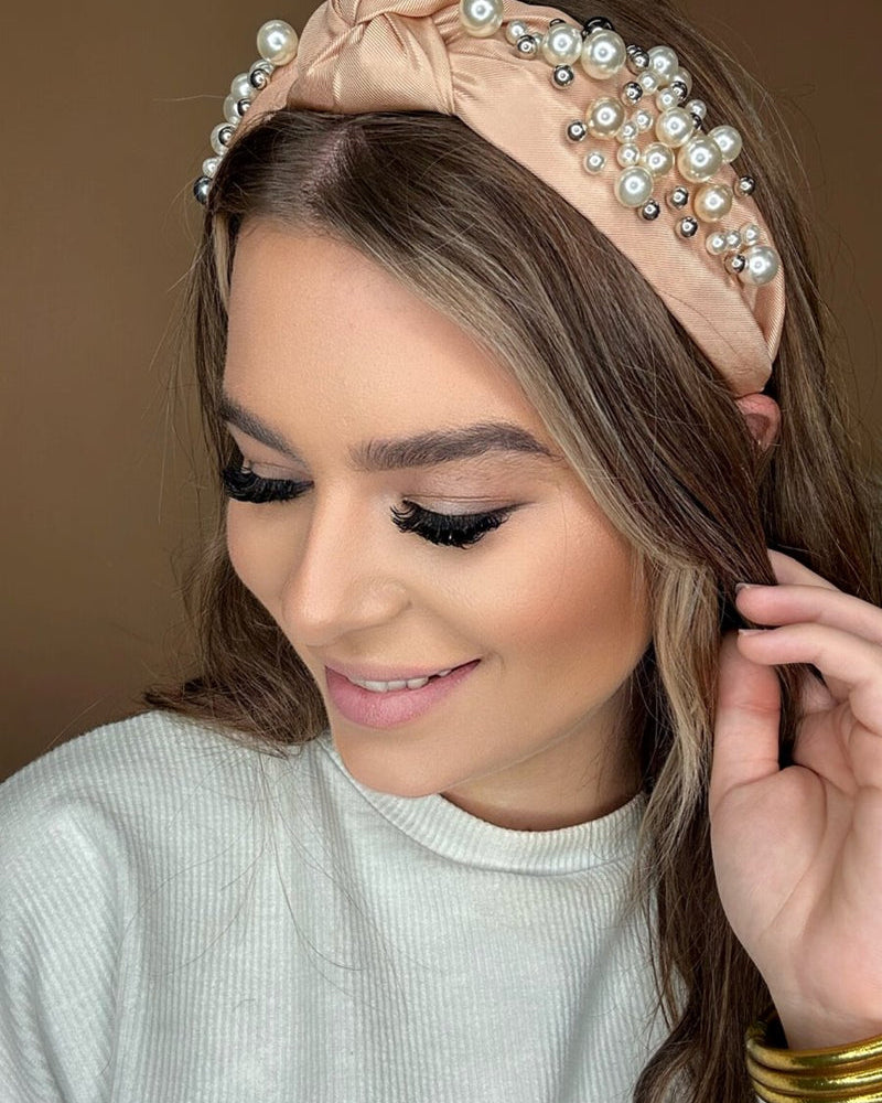 a twisted center knot headband with varying sizes of pearl detailing in champagne
