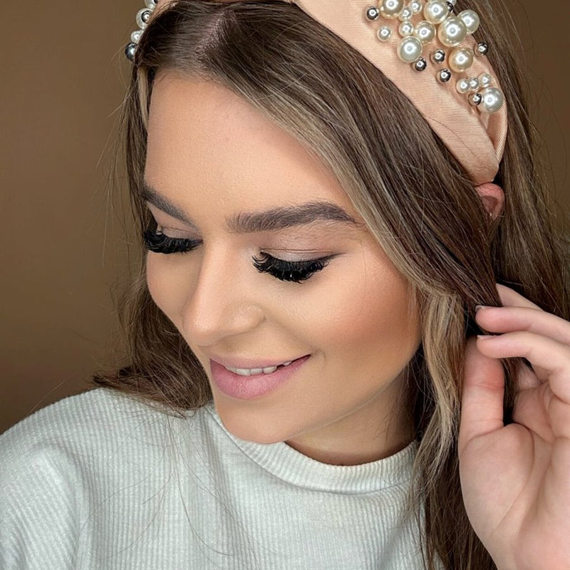 a twisted center knot headband with varying sizes of pearl detailing in champagne