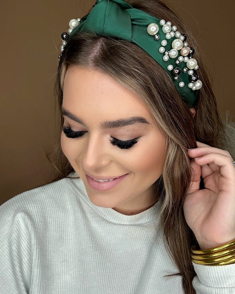 a twisted center knot headband with varying sizes of pearl detailing in green