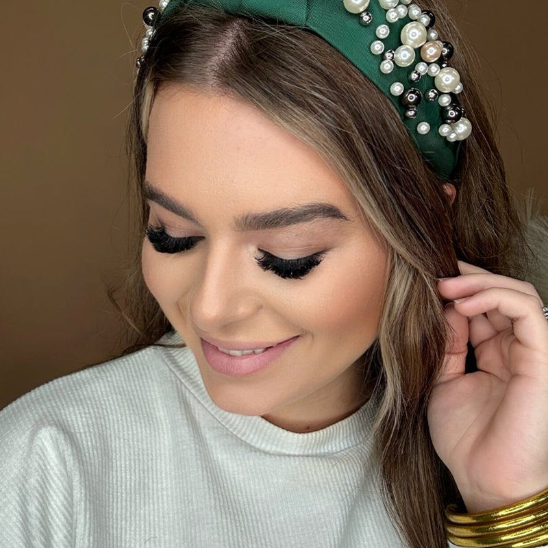 a twisted center knot headband with varying sizes of pearl detailing in green