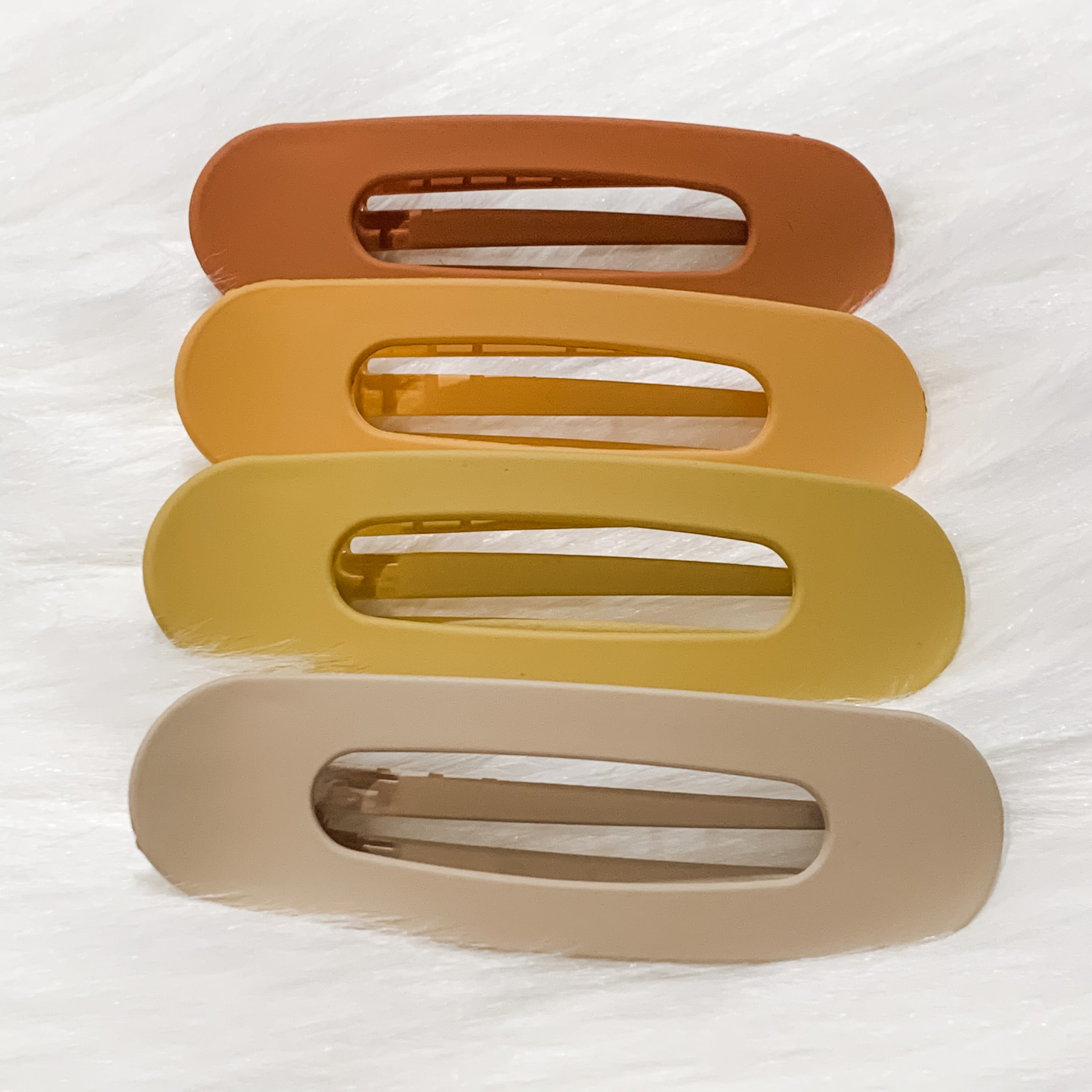oversized spring back clip with curve design in terracotta, peach, mustard, and neutral