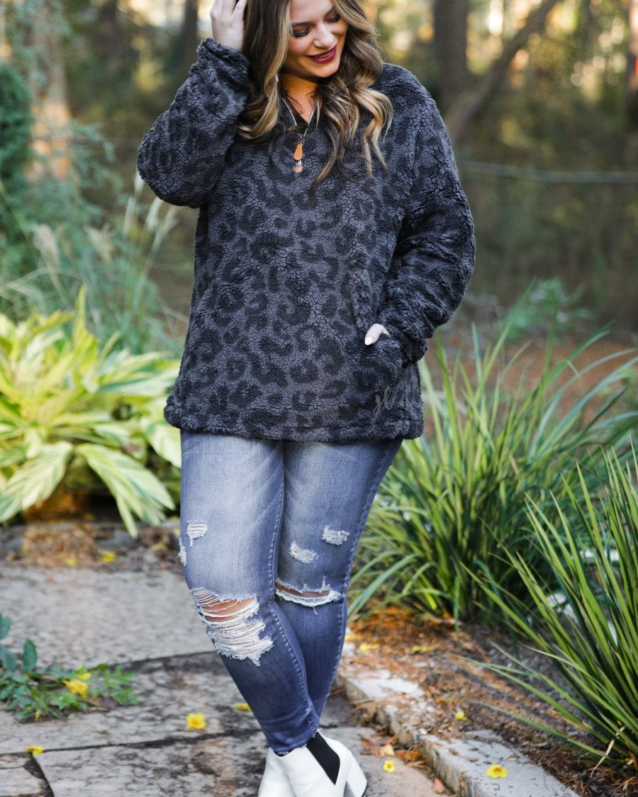 a long-sleeve fluffy pullover with a quarter zip, convenient pockets, and a foldable collar on a black leopard sherpa fabric