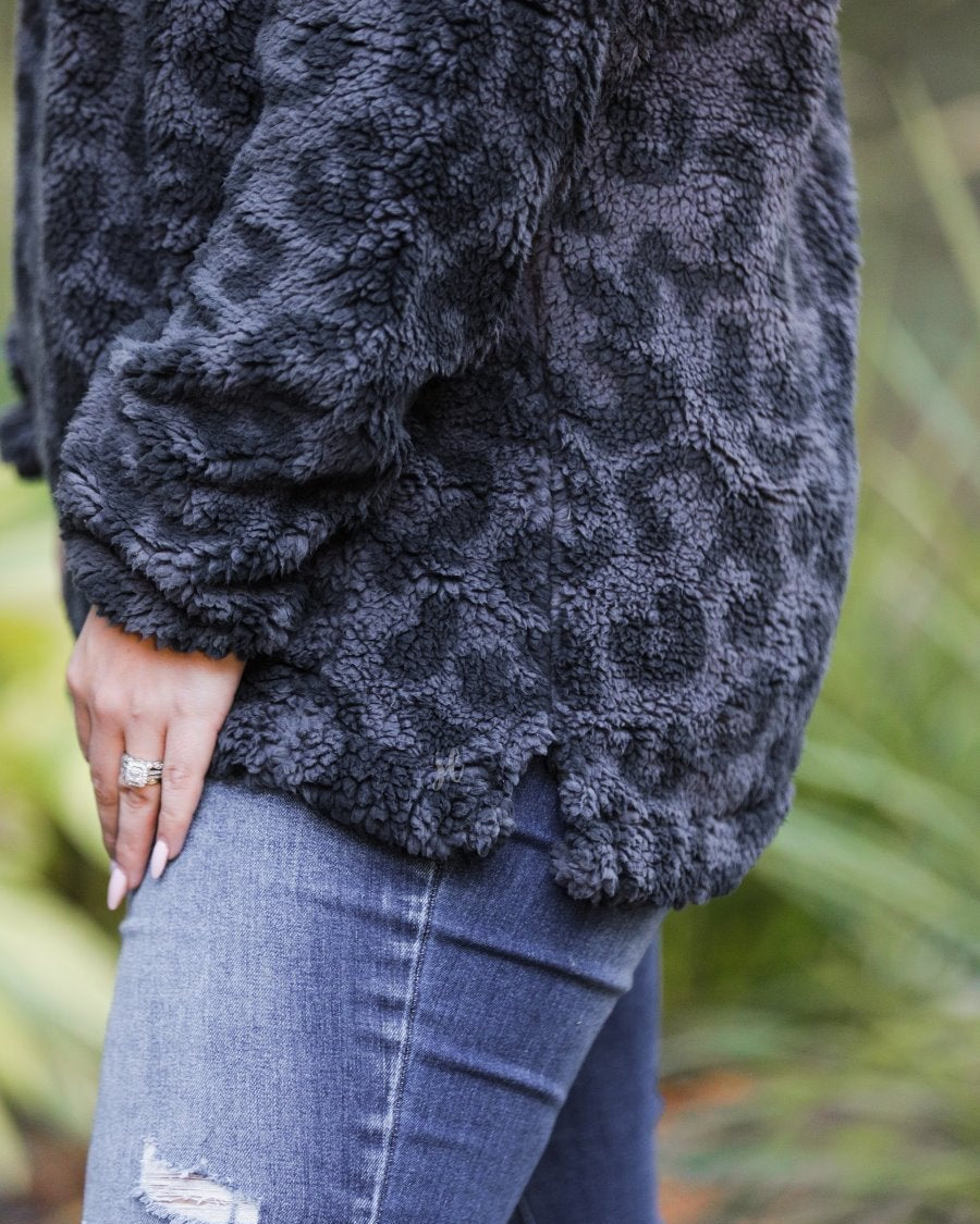 a long-sleeve fluffy pullover with a quarter zip, convenient pockets, and a foldable collar on a black leopard sherpa fabric