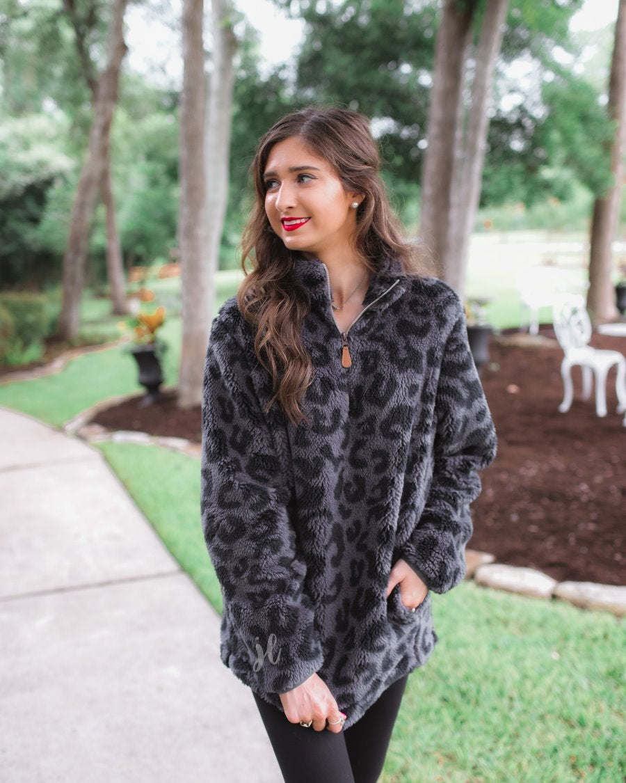 a long-sleeve fluffy pullover with a quarter zip, convenient pockets, and a foldable collar on a black leopard sherpa fabric