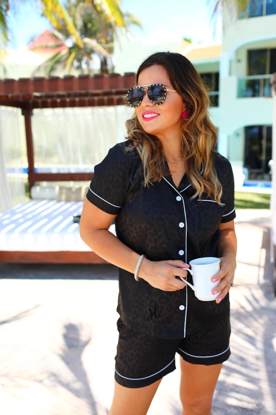 a black satin two-piece lounge set sold together with a tonal leopard pattern, collared button-down top, short sleeves, a chest pocket, piped trim, and matching shorts with an elastic drawstring waist and accent side pockets
