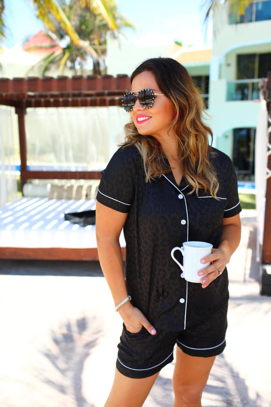 a black satin two-piece lounge set sold together with a tonal leopard pattern, collared button-down top, short sleeves, a chest pocket, piped trim, and matching shorts with an elastic drawstring waist and accent side pockets