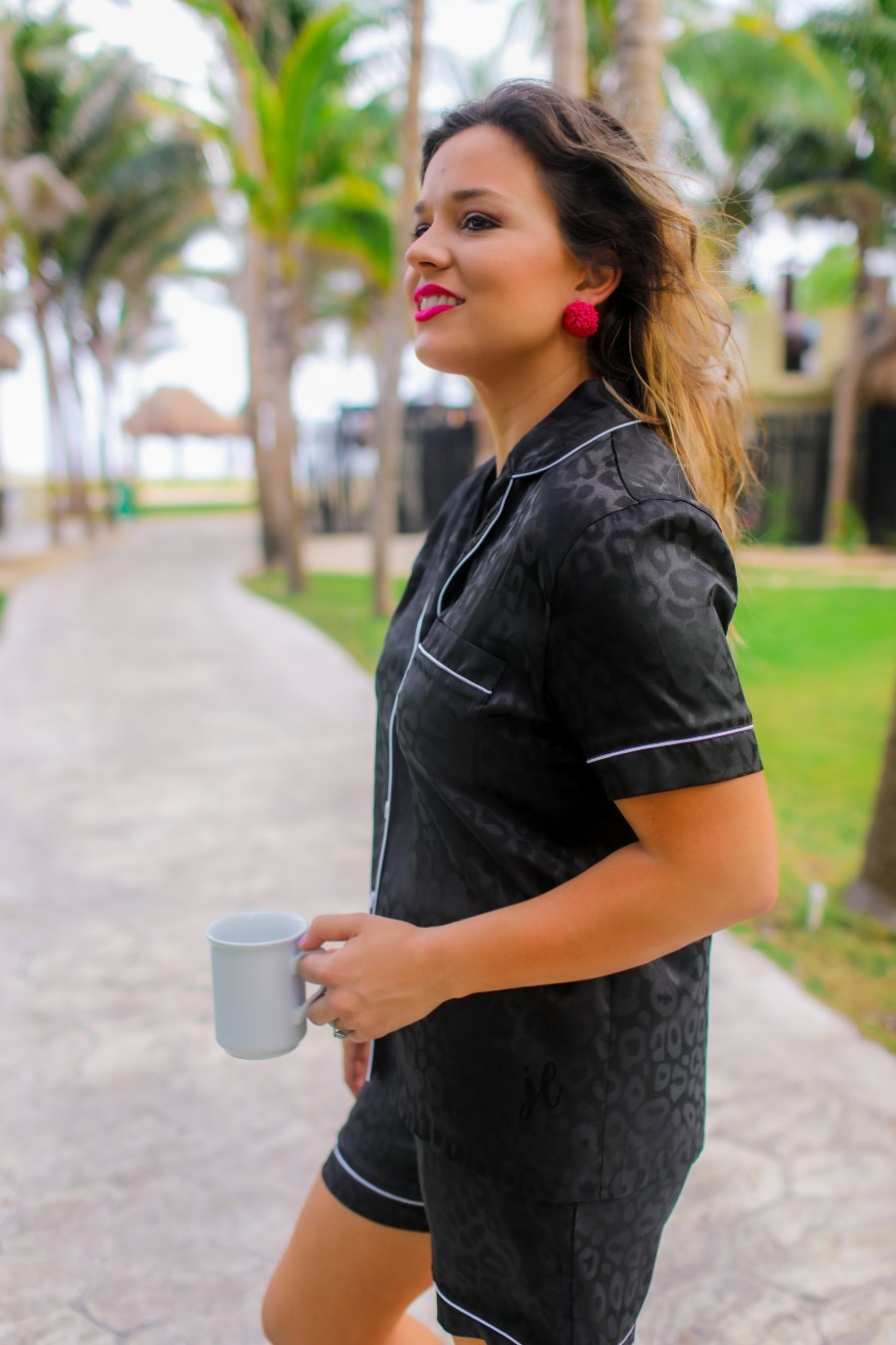 a black satin two-piece lounge set sold together with a tonal leopard pattern, collared button-down top, short sleeves, a chest pocket, piped trim, and matching shorts with an elastic drawstring waist and accent side pockets