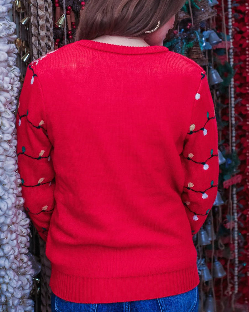 a red long-sleeve heavy sweater made of soft, cozy material with a cheerful reindeer graphic framed by delicate snowflakes, playful snowflake accents, and whimsical multicolor light strands wrapping around the sleeves