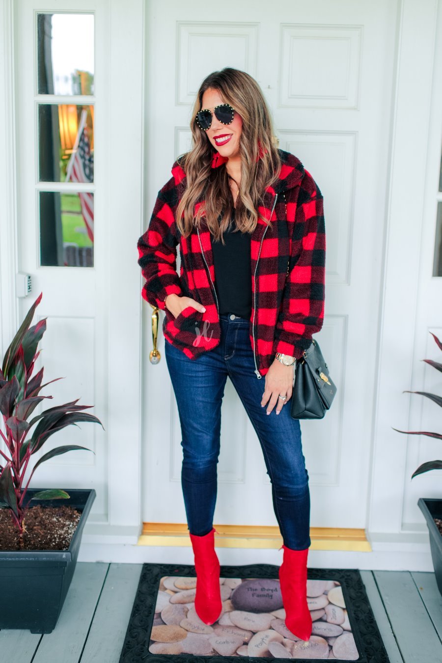 long-sleeve jacket made of fluffy fleece material with a full zipper, an elastic waistband, pockets, and a foldable collar on black and red buffalo plaid fabric