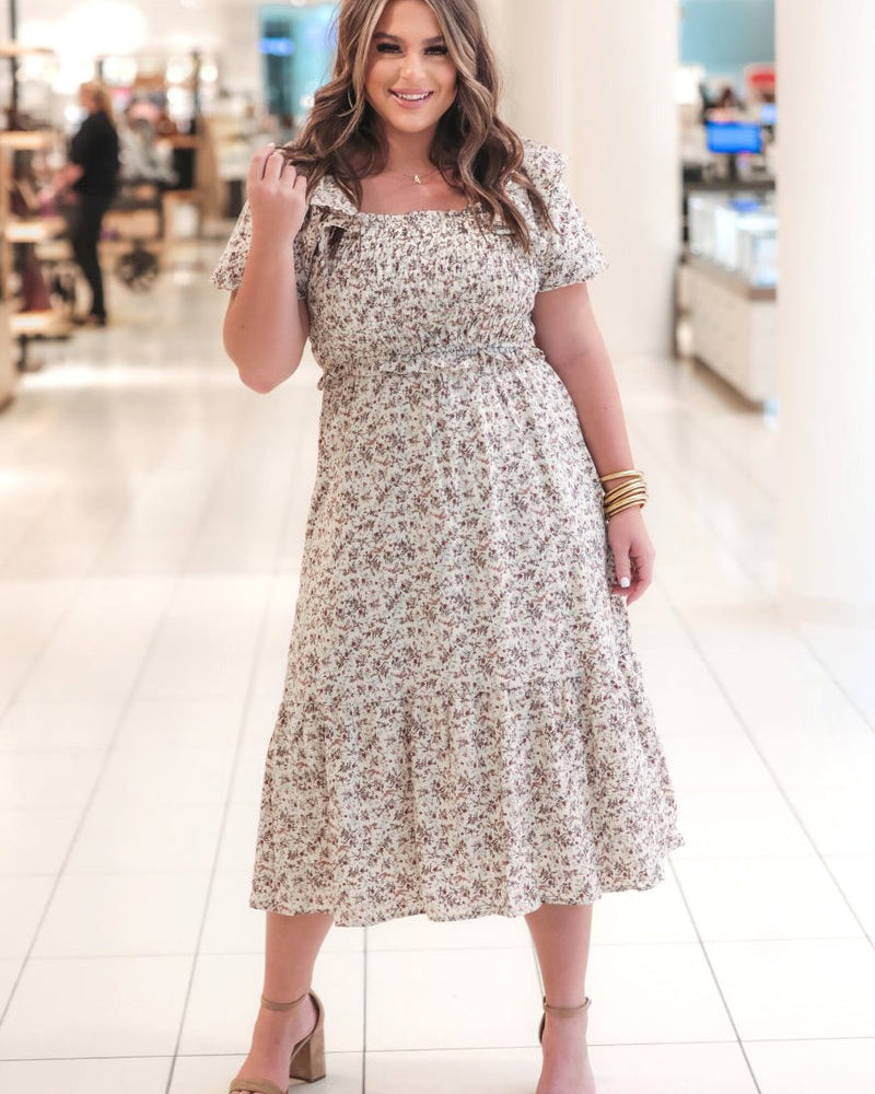 a lightweight ditsy floral midi dress with a smocked bodice, square neckline, ruffled trim and cap sleeves (wearable on or off the shoulder), and a relaxed silhouette that falls into a mid-calf hemline