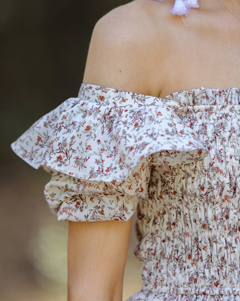 a lightweight ditsy floral midi dress with a smocked bodice, square neckline, ruffled trim and cap sleeves (wearable on or off the shoulder), and a relaxed silhouette that falls into a mid-calf hemline