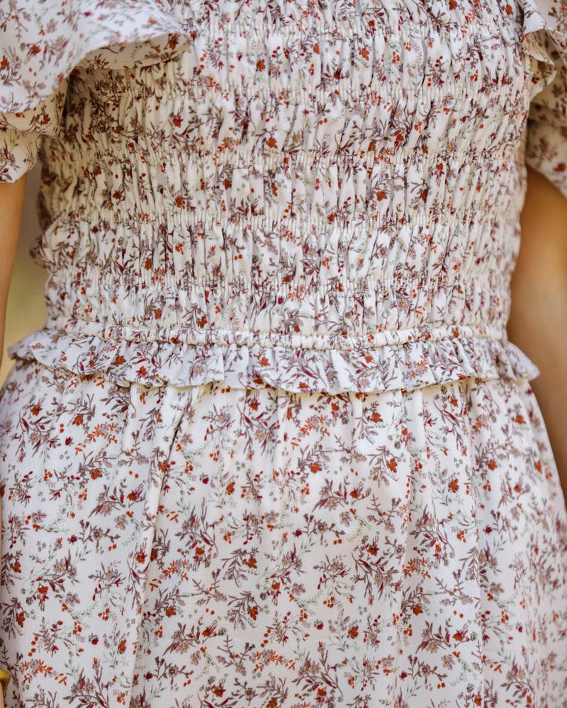 a lightweight ditsy floral midi dress with a smocked bodice, square neckline, ruffled trim and cap sleeves (wearable on or off the shoulder), and a relaxed silhouette that falls into a mid-calf hemline