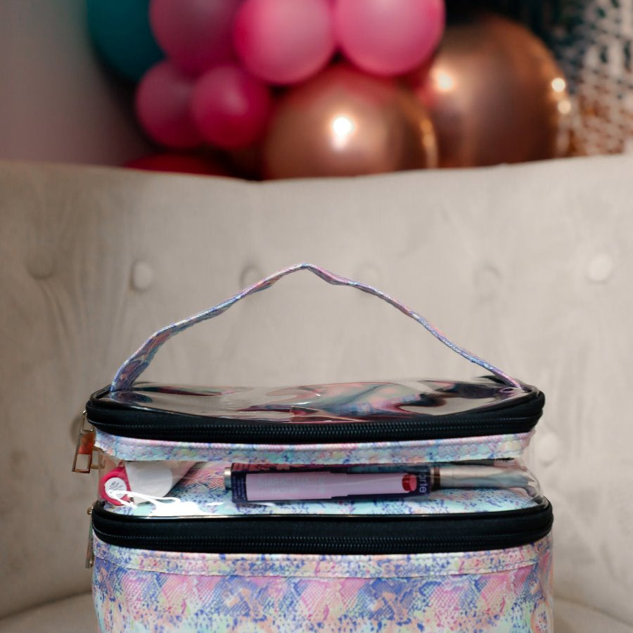 two-tier design with a clear compartment, four brush slots with an elastic band on the inside lid of the main compartment, and a grab-and-go handle with dual gold zippers in a soft pastel snakeskin print
