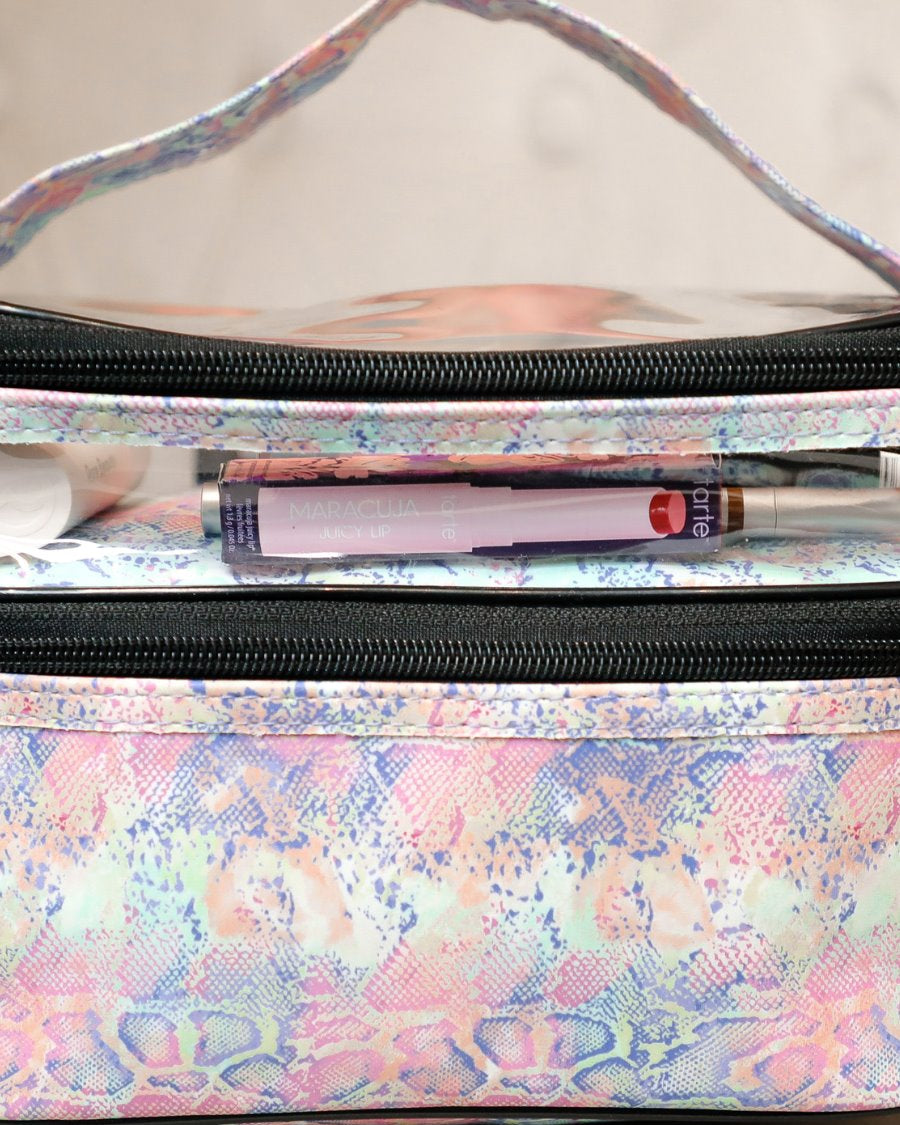 two-tier design with a clear compartment, four brush slots with an elastic band on the inside lid of the main compartment, and a grab-and-go handle with dual gold zippers in a soft pastel snakeskin print