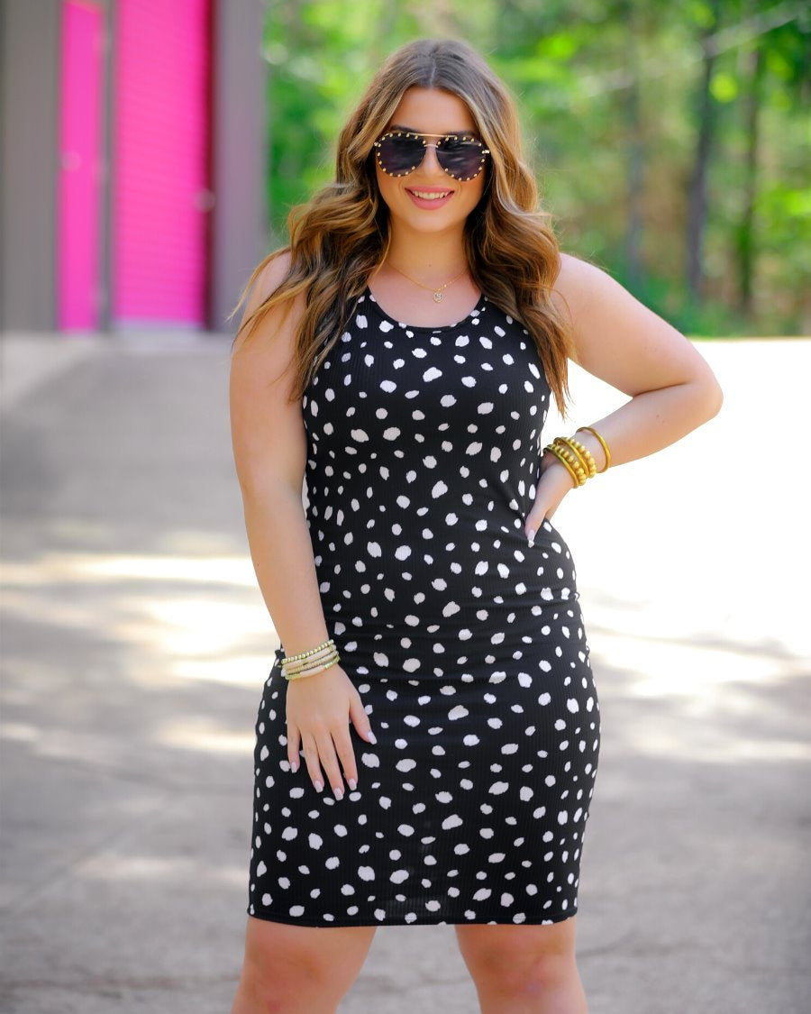 a lightweight midi bodycon dress with a flattering ribbed knit, a sleeveless silhouette, and a scoop neckline on a solid black base and white polka dot print fabric