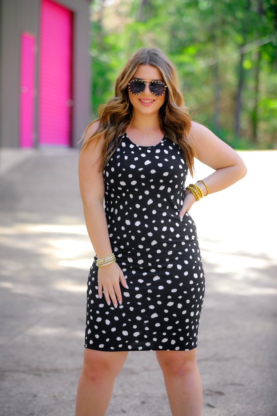 a lightweight midi bodycon dress with a flattering ribbed knit, a sleeveless silhouette, and a scoop neckline on a solid black base and white polka dot print fabric