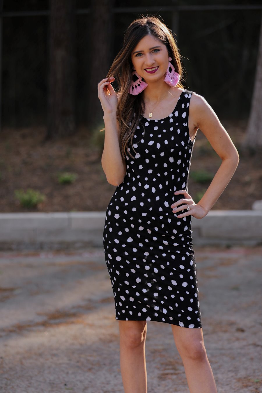 a lightweight midi bodycon dress with a flattering ribbed knit, a sleeveless silhouette, and a scoop neckline on a solid black base and white polka dot print fabric