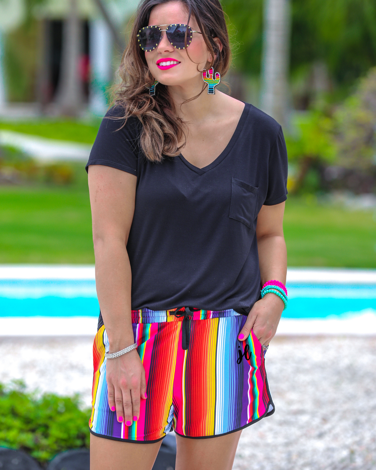 mid-rise relaxed fit activewear shorts with side pockets and a tie waist drawstring with gold bead accents, designed on a multicolor serape pattern print fabric and black trim