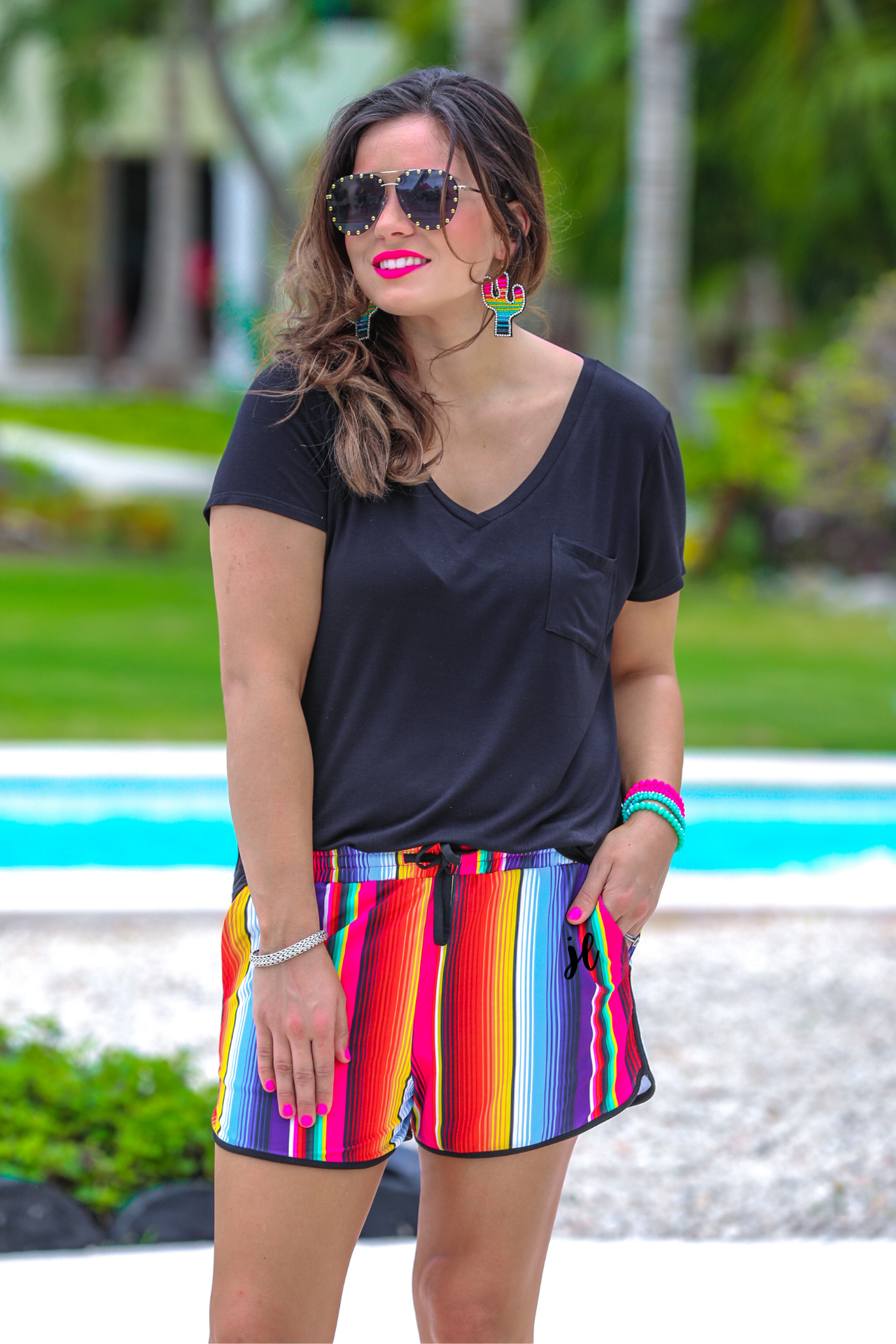 mid-rise relaxed fit activewear shorts with side pockets and a tie waist drawstring with gold bead accents, designed on a multicolor serape pattern print fabric and black trim