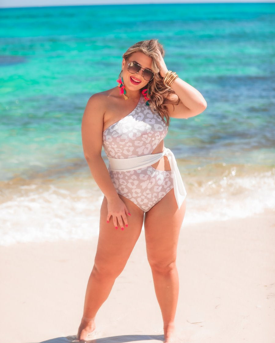 stretchy one-shoulder one-piece swimsuit with a flirty side cutout, wraparound waist tie, and removable padding on a subtle leopard pattern print fabric